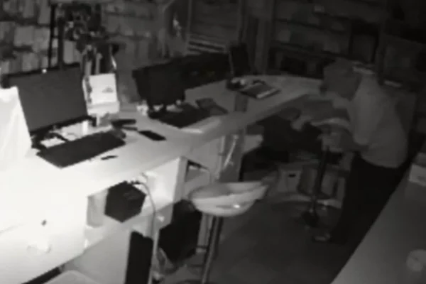 Imagem de uma câmera de segurança de uma loja de roupa mostrando um homem furtando dinheiro de um caixa - Metrópoles