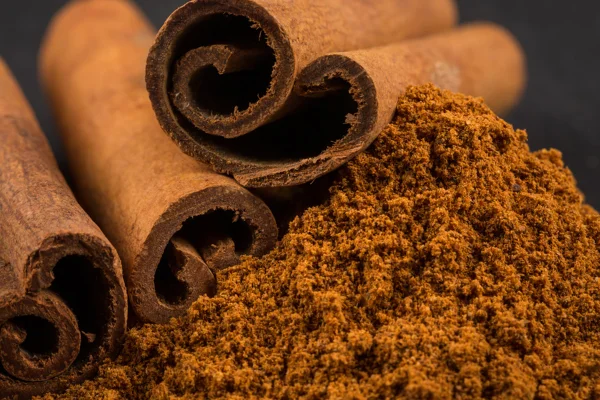 Foto corolida com zoom de uma especiaria chamada canela. Mostra o tempero em forma de farinha e em forma de caule - Metrópoles.