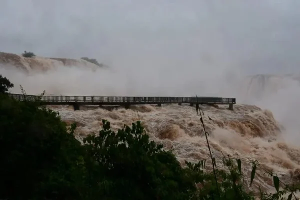 Foto mostra cheia nas Cataratas do Iguaçu, na fronteira entre o Paraná e a Argentina, com fortes ondas de água de coloração amarronzada - Metrópoles