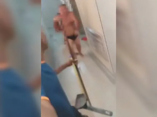 Imagem de homem de sunga correndo em direção a homem com rodo na mão - Metrópoles