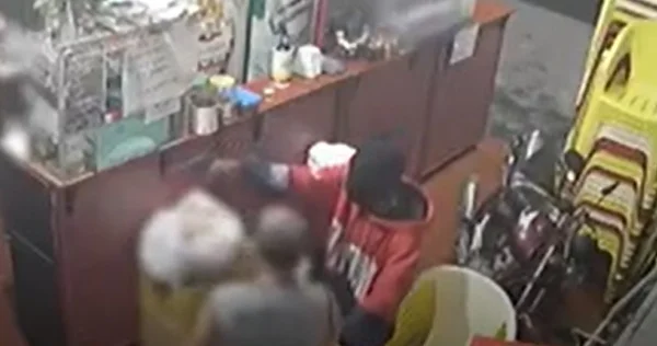 Imagem pouco nítida de assaltante rendendo clientes dentro de um bar - Metrópoles