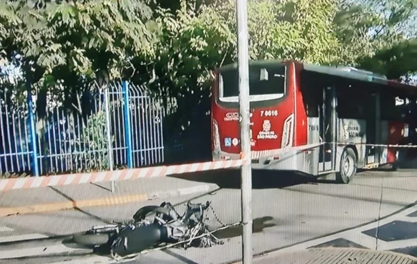 Imagem colorida de moto no chão após batida com ônibus