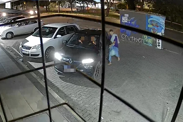 Imagem colorida de um homem de camisa azul abrindo a porta de um carro preto com duas pessoas dentro