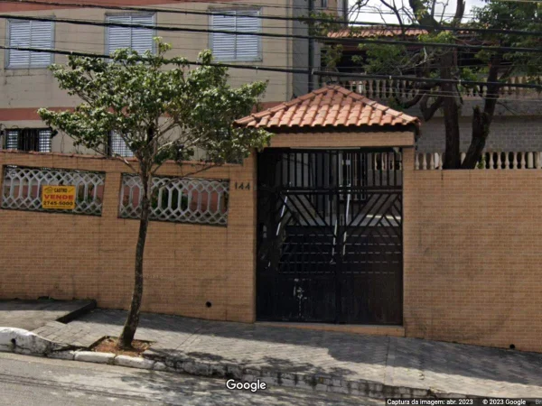 Imagem colorida mostra fachada de prédio beje com tijolos à vista e árvore na frente - Metrópoles