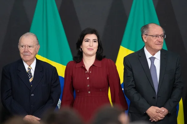 A cerimônia de posse da ministra do Planejamento e Orçamento, Simone Tebet, realizada no Salão Nobre do Palácio do Planalto. Na foto, a ministra aparece ladeada por José Sarney e Geraldo Alckmin no palco, com bandeiras do Brasil atrás - Metrópoles