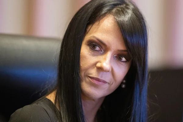 Foto colorida de mulher de cabelo grande e preto em depoimento