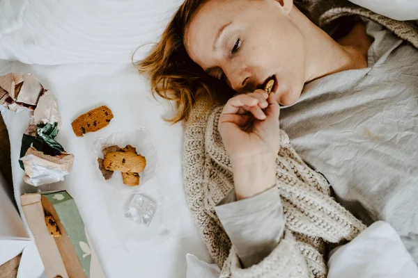 Imagem colorida de pessoa comendo biscoito e parecendo forçada - Metropóles