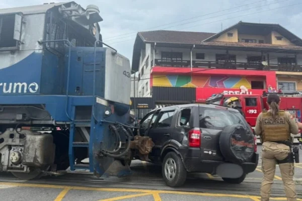 Foto colorida de carro atingido por trem em Joinville - Metrópoles