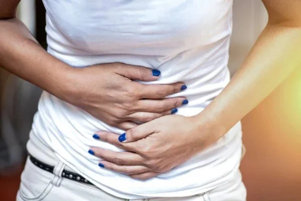 Foto de uma mulher com as duas mãos pressionadas sobre a barriga