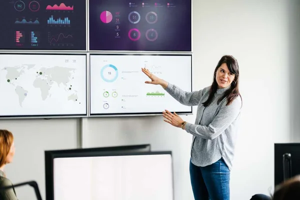 Na foto, há uma mulher apontando para um quadro com gráficos - Metrópoles