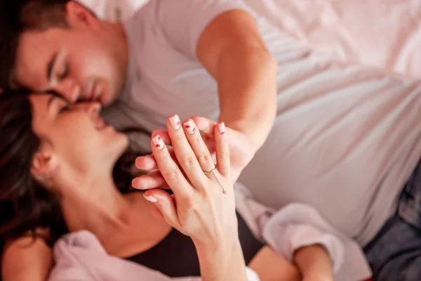 Imagem colorida de casal na cama dando as mãos