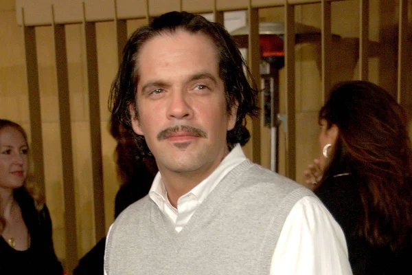 foto colorida de homem branco de cabelos médios e bigode usando camisa branca e colete cinza - metrópoles