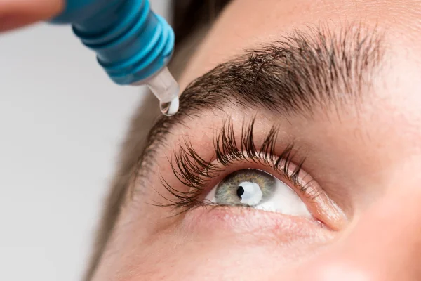 Imagem mostra homem de olhos verdes pingando um colírio - Metrópoles