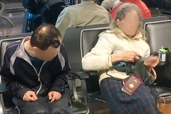 Idosa e homem com down em banco de aeroporto - Metrópoles
