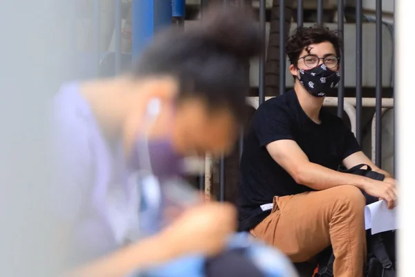 Fotografia colorida de dois jovens antes da entrada para realização do Enem em 2021 Provas do Enem 2021