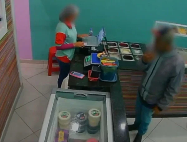 Imagem de atendente pesando sorvete; homem observa do outro lado balcão - Metrópoles