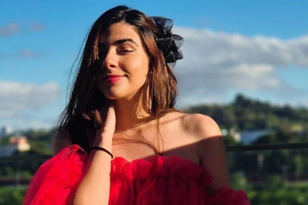 Foto colorida de uma mulher branca. com vestido vermelho e batom vermelho - Metrópoles