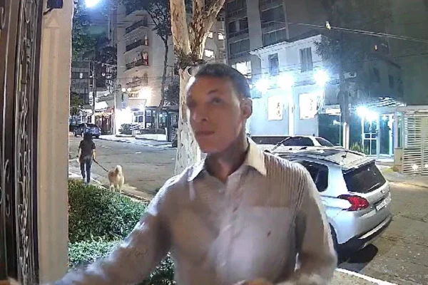 Imagem colorida mostra homem vestido de roupa social tentando entrar no prédio de Fabio Wajngarten - Metrópoles