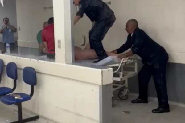 Imagem colorida de um homem branco, em surto e nu, sendo socorrido por bombeiros em uma maca de hospital. Paciente estava em surto - Metrópoles