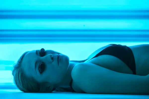 Mulher usando óculos de proteção em cabine de bronzeamento artificial