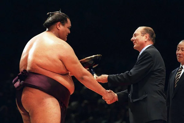 Imagem colorida do lutador de sumô Taro Akebono recebendo prêmio - Metrópoles