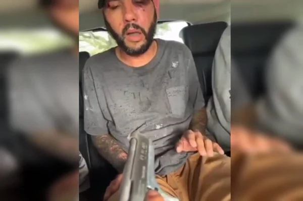 Homem simulando tortura sob a mira de uma arma