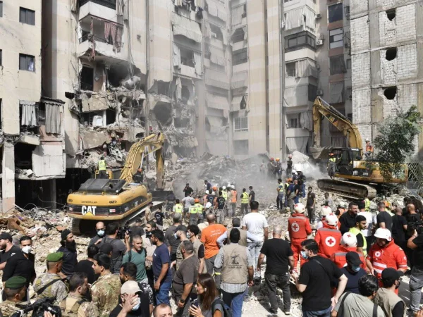 Foto colorida de oficiais usando equipamento de construção para remover destroços após o ataque aéreo do exército israelense no distrito de Dahieh, no sul de Beirute - Metrópoles