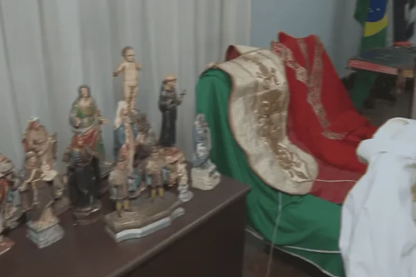 Imagem colorida de diversas imagens de santos religiosos em cima de uma escrivaninha de madeira - Metrópoles