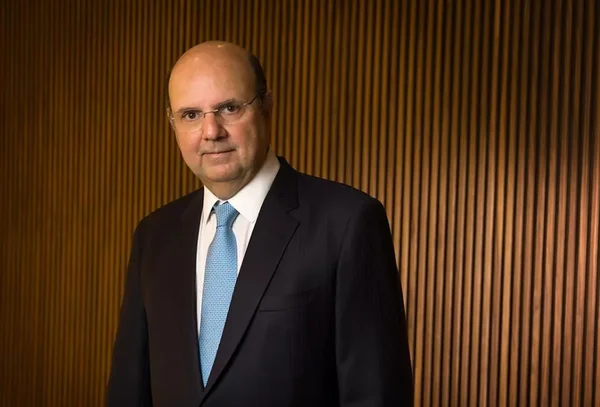 Imagem do advogado Ricardo Tosto, sócio-fundador do Leite, Tosto e Barros Advogados. Ele está de terno escuro, gravata azul clara e camisa branca. Ele é careca é usa óculos. Ao fundo, uma parede marrom - Metrópoles