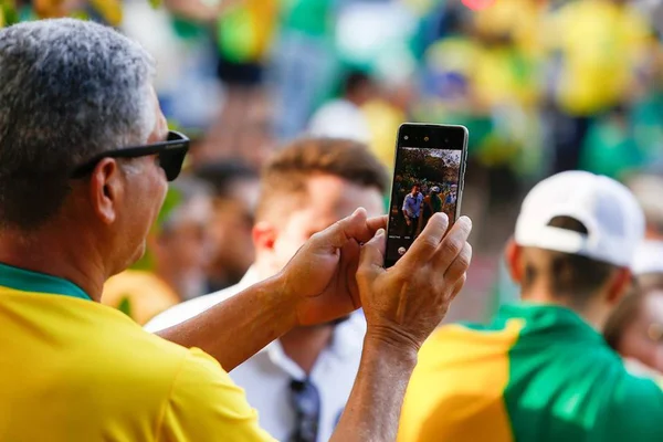 Imagem colorida de militante bolsonarista tira foto em ato político