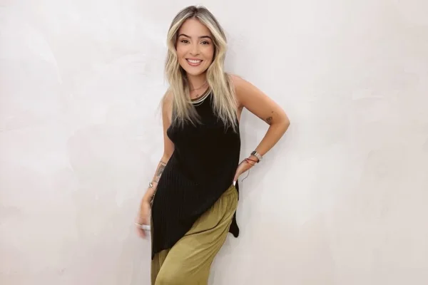 Imagem colorida mostra mulher branca de camisa preta e saia verde - Metrópoles