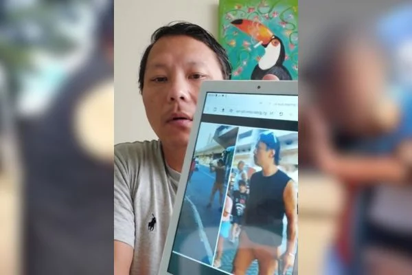 Imagem colorida mostra o policial Paulo Hyun Bae Kim, um homem oriental, de cabelos pretos, vestindo uma camiseta cinza e segurando um tablet com uma foto dele, vestido de preto durante uma confusão na frente do Metrô Carandiru, em São Paulo, na qual ele é acusado de agressão contra um jovem que tentou roubar sua esposa - Metrópoles