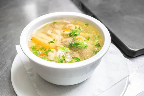 Tigela com canja de galinha quente em talheres brancos