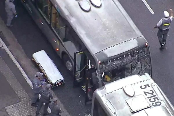 Imagem colorida mostra vidro da frente de um ônibus quebrado. Veículo está quase encostado na traseira de outro ônibus - Metrópoles