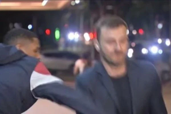Imagem colorida mostra ciclista tentando roubar celular de repórter da Bandeirantes - Metrópoles