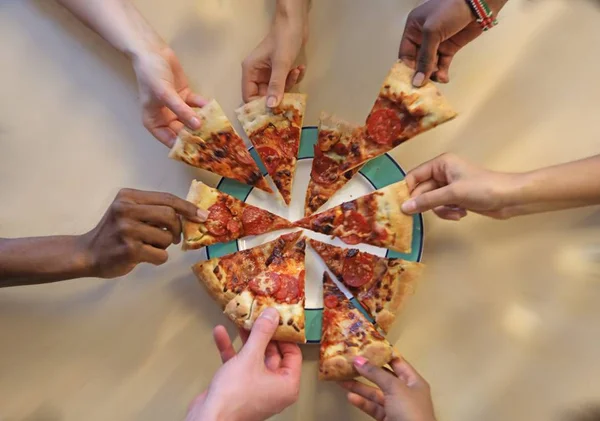 Mãos pegando fatias de pizza