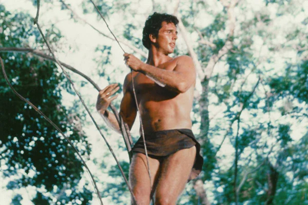 Imagem colorida de homem usando tanga, sem camisa e pendurado em árvore - Metrópoles