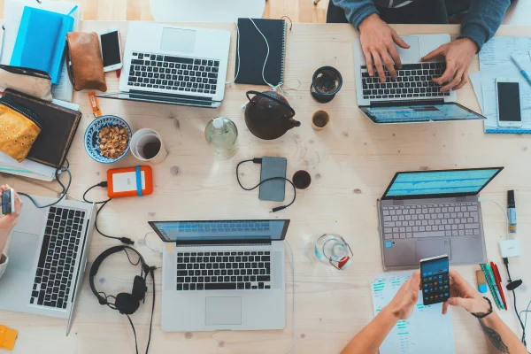 Foto colorida de uma mesa com vários computadores - Metrópoles