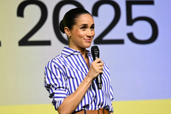 Foto colorida de mulher com blusa listrada falando ao microfone - Metrópoles