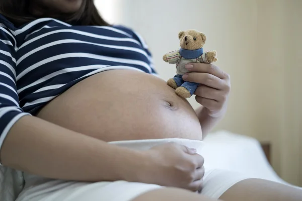 jovem grávida segurando um urso de pelúcia