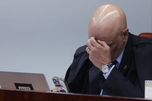 Moraes, de cabeça baixa, examinando o celular -- Metrópoles