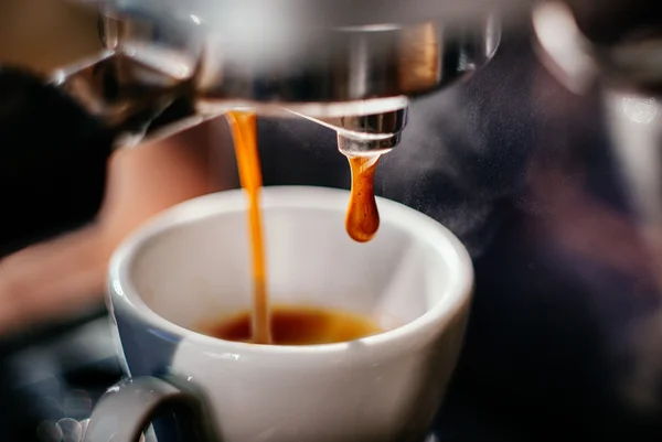 Imagem colorida de cafeteira com café caindo diretamente na xícara - Metrópoles