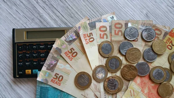 Fotografia colorida mostrando notas e moedas sobre calculadora-Metrópoles