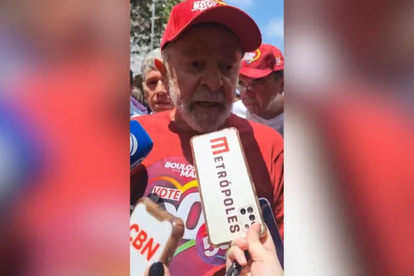 Imagem colorida mostra o presidente Lula dando entrevista vestindo camiseta e boné vermelhos - Metrópoles