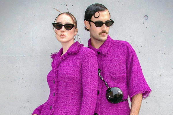 Casal com roupas roxas posando para a foto. Os dois também usam óculos de sol - Metrópoles