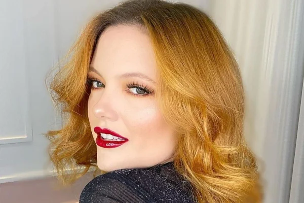 Lari Rosa, influencer de Anápolis que debochou de vagas destinadas a autistas. Ela olha por cima do ombro para a câmera, sorrindo, e tem olhos verde, cabelo acobreado e batom vermelho - Metrópoles