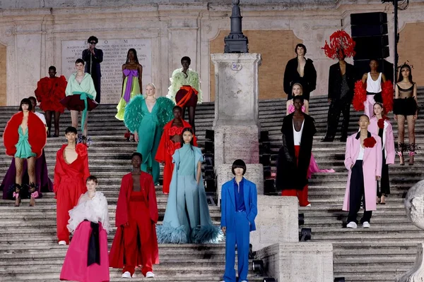 Fila final do desfile de Alta-Costura da marca Valentino. Na foto, é possível ver as modelos com as roupas posicionadas em uma escadária de um monumento histórico de Roma, na Itália, onde ocorreu o evento.