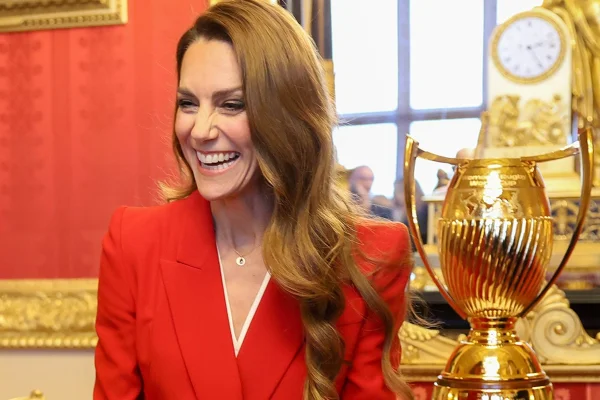 Princesa Kate Middleton sorrindo ao lado de uma taça dourada