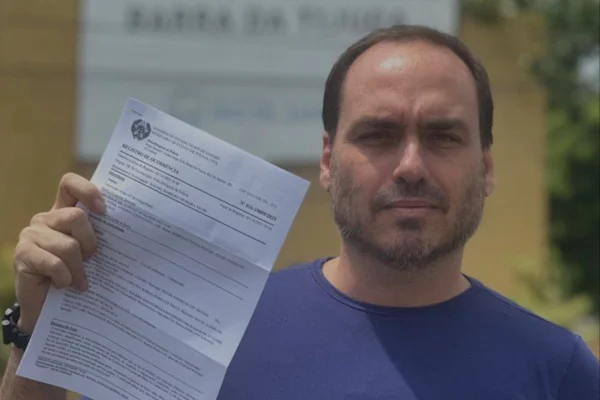 Imagem colorida de Carlos Bolsonaro com um boletim de ocorrência na mão - Metrópoles
