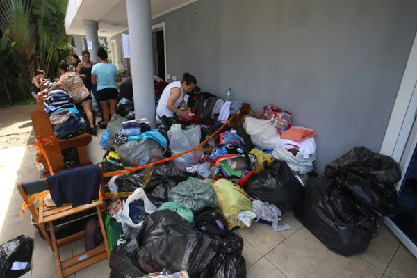 Imagem colorida com famílias proximo ao local de doação de roupas após fortes chuvas no Litoral Norte de SP - Metrópoles